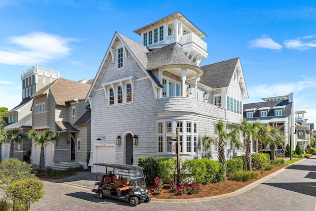 view of front of home featuring a balcony, driveway, an attached garage, and roof with shingles
