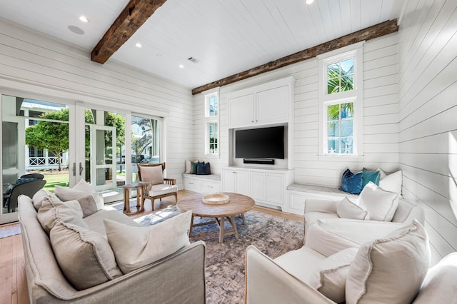 living room featuring wooden walls, light wood-style floors, french doors, and beamed ceiling