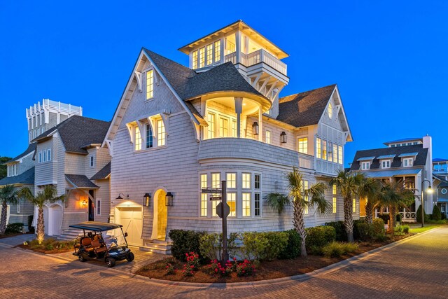 victorian house featuring roof with shingles, a balcony, and a garage