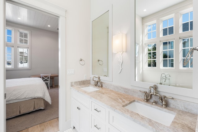 ensuite bathroom featuring connected bathroom, recessed lighting, a sink, and wood finished floors