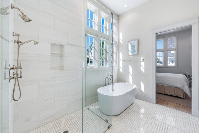 ensuite bathroom featuring a freestanding tub, tile patterned floors, ensuite bath, a stall shower, and baseboards