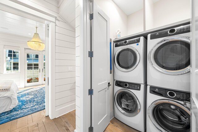 clothes washing area featuring hardwood / wood-style floors, stacked washing maching and dryer, and laundry area