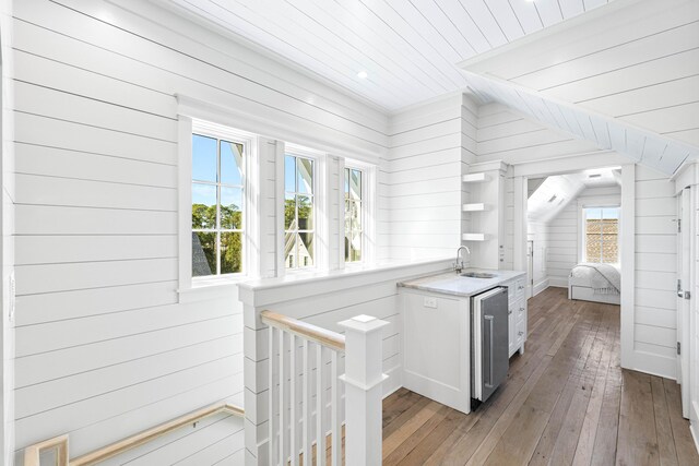 interior space featuring a sink, wood walls, wooden ceiling, light wood-type flooring, and vaulted ceiling