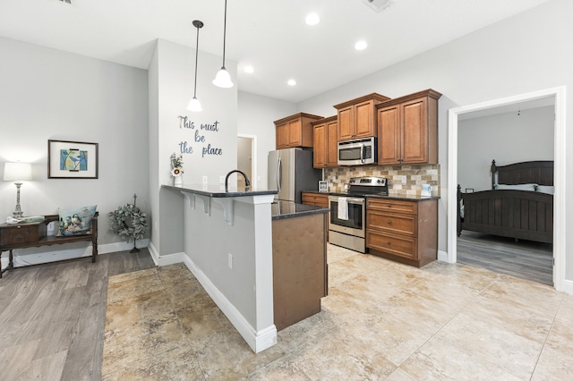 472 W College Blvd, Valparaiso, FL 32580 - kitchen featuring appliances with stainless steel finishes, brown cabinets, a peninsula, tasteful backsplash, and a kitchen breakfast bar