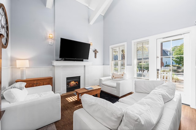 265 Salt Box Ln, Watersound, FL 32461 - living room with a brick fireplace, wood finished floors, beamed ceiling, high vaulted ceiling, and a wainscoted wall