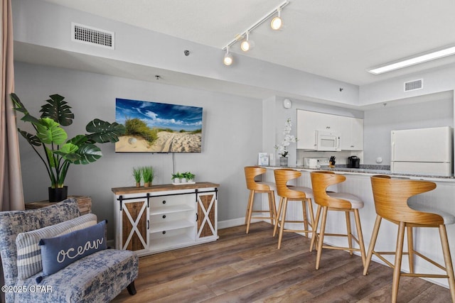 9900 S Thomas Dr Unit 1408, Panama City Beach, FL 32408 - kitchen with wood finished floors, visible vents, white cabinetry, and white appliances