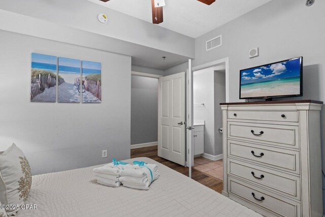9900 S Thomas Dr Unit 1408, Panama City Beach, FL 32408 - bedroom featuring ensuite bathroom, visible vents, baseboards, a ceiling fan, and wood finished floors