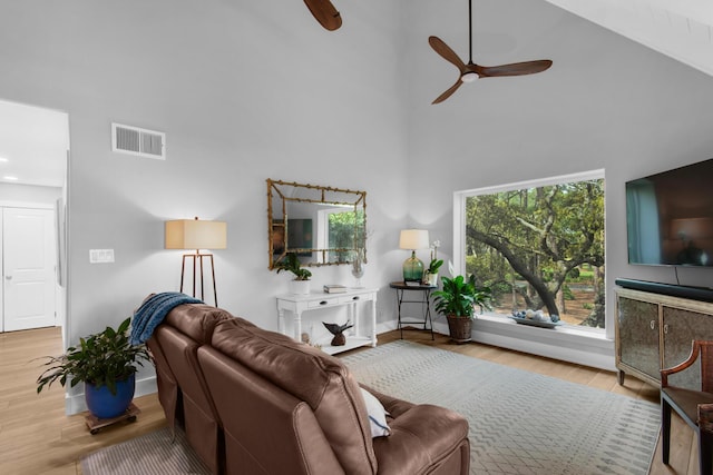 living room with wood finished floors, a towering ceiling, a ceiling fan, and visible vents