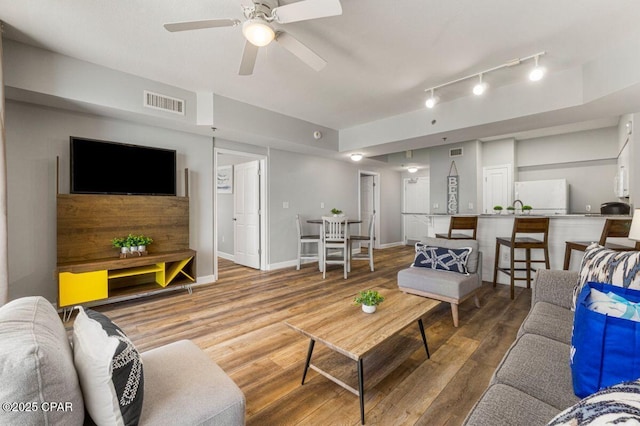 living area featuring ceiling fan, visible vents, and wood finished floors