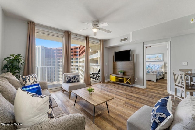 living area with plenty of natural light, visible vents, wood finished floors, and a ceiling fan