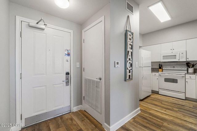 foyer with dark wood-type flooring, baseboards, and visible vents