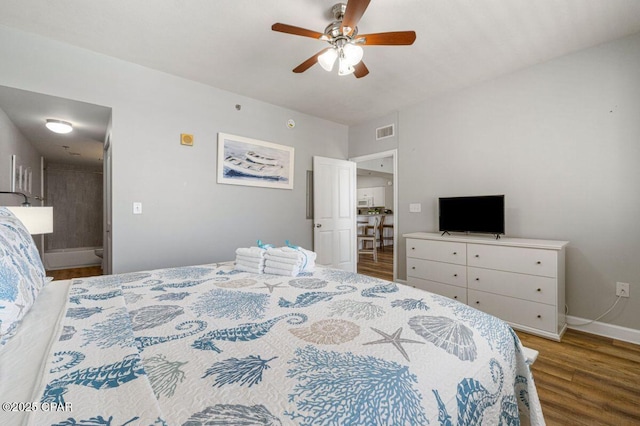 bedroom featuring baseboards, ceiling fan, visible vents, connected bathroom, and wood finished floors
