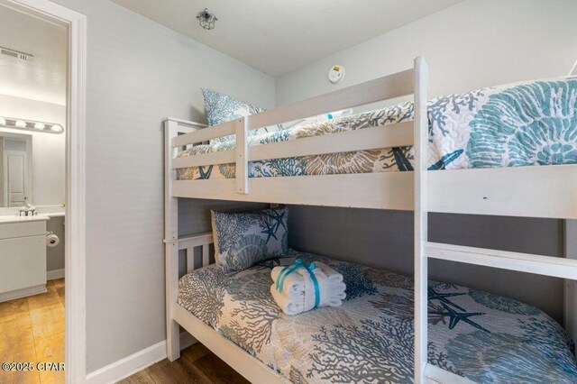 bedroom with baseboards, visible vents, and wood finished floors