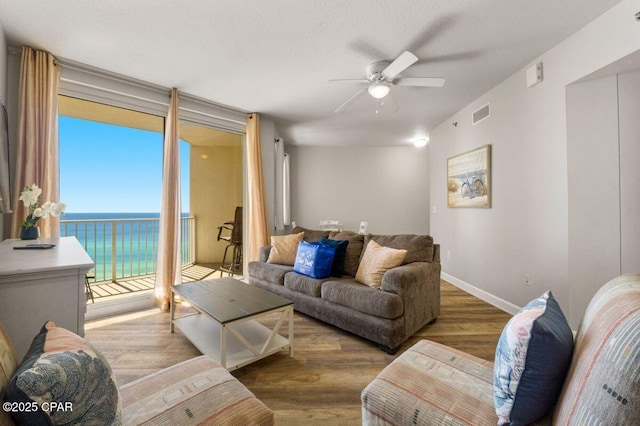 9900 S Thomas Dr Unit 1410, Panama City Beach, FL 32408 - living area featuring a ceiling fan, visible vents, wood finished floors, baseboards, and a water view