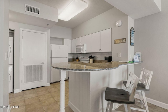 9900 S Thomas Dr Unit 1410, Panama City Beach, FL 32408 - kitchen featuring white appliances, a kitchen breakfast bar, visible vents, and stacked washer / dryer