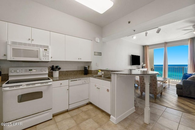 9900 S Thomas Dr Unit 1410, Panama City Beach, FL 32408 - kitchen with white cabinets, backsplash, white appliances, and open floor plan