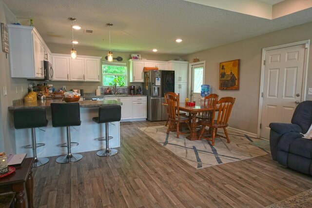 5594 Riviera Dr, Milton, FL 32583 - kitchen featuring light wood-style floors, a peninsula, white cabinetry, and black refrigerator with ice dispenser