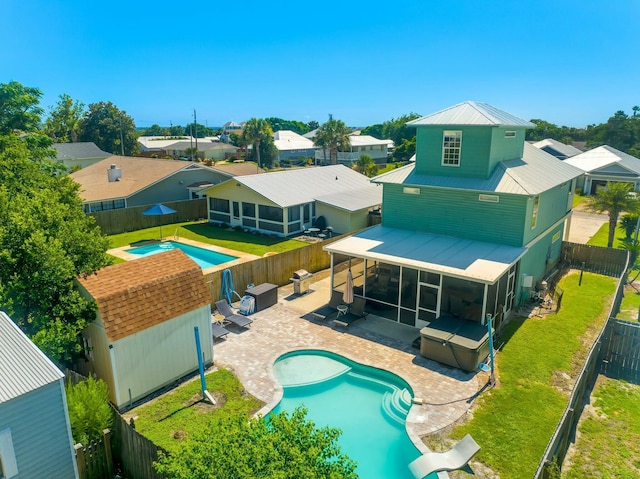 rear view of property featuring a fenced backyard, a fenced in pool, a sunroom, and a patio area