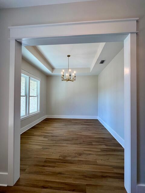 149 Leap Year Ln, Freeport, FL 32439 - unfurnished dining area with a notable chandelier, dark wood-type flooring, baseboards, a raised ceiling, and visible vents