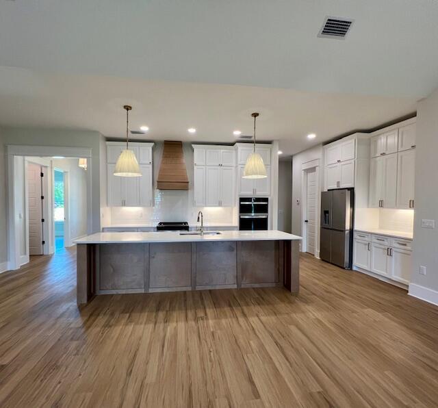 149 Leap Year Ln, Freeport, FL 32439 - kitchen with stainless steel fridge with ice dispenser, wall chimney range hood, light wood-type flooring, and a sink