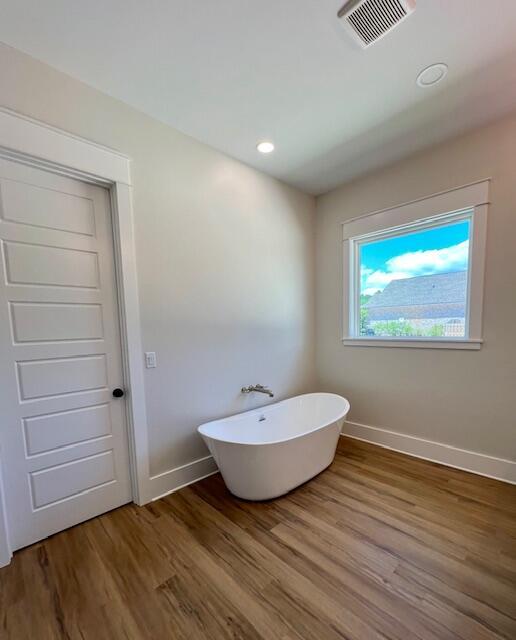 149 Leap Year Ln, Freeport, FL 32439 - bathroom with baseboards, visible vents, wood finished floors, and a freestanding tub