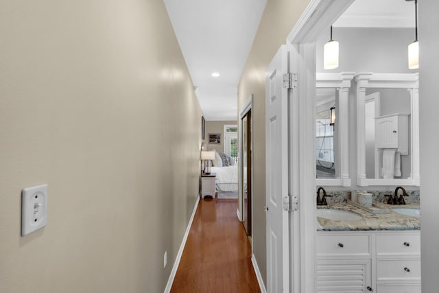 corridor featuring baseboards, a sink, dark wood-style floors, and recessed lighting