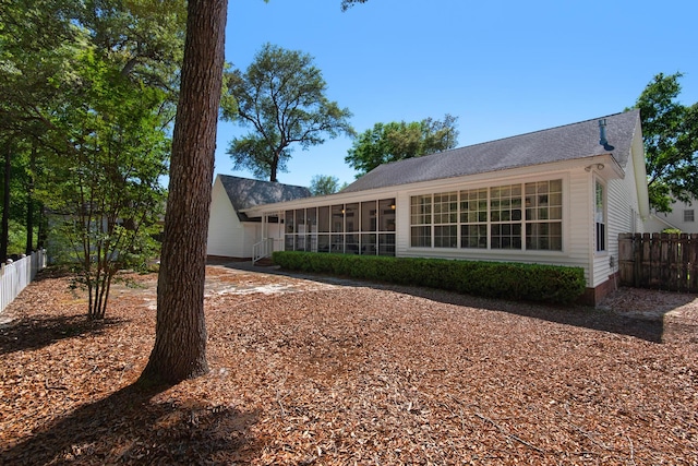 rear view of property featuring a sunroom and fence