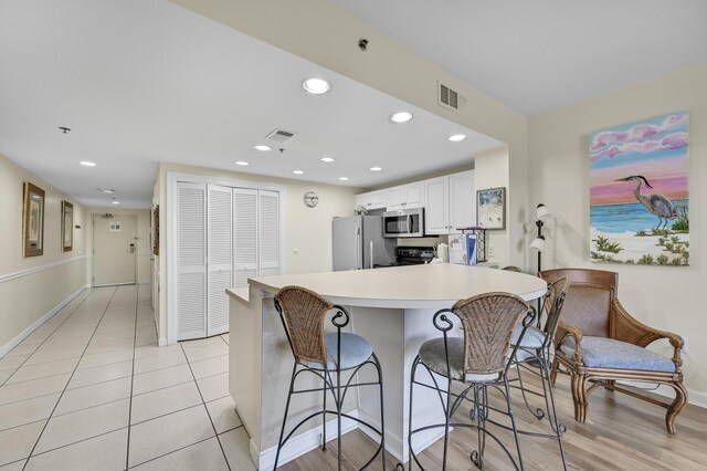 1751 Scenic Highway 98 Unit 212, Destin, FL 32541 - kitchen with appliances with stainless steel finishes, a breakfast bar, baseboards, white cabinetry, and a peninsula