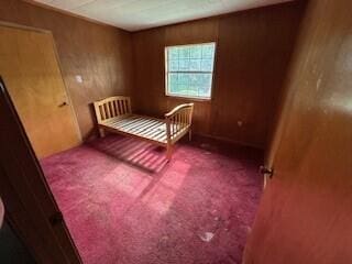 carpeted bedroom featuring wooden walls