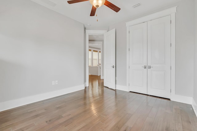 unfurnished bedroom with wood finished floors, a closet, a ceiling fan, and baseboards