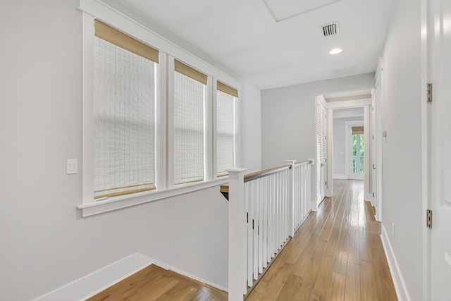 hallway with baseboards, light wood-style floors, recessed lighting, and an upstairs landing