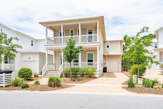 view of front of home featuring a balcony, a porch, a garage, decorative driveway, and a standing seam roof