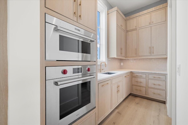 160 Heritage Dunes Ln S, Santa Rosa Beach, FL 32459 - kitchen with light brown cabinetry, light wood finished floors, stainless steel double oven, a sink, and light countertops