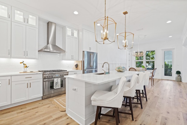 90 Basal St, Inlet Beach, FL 32461 - kitchen with high end appliances, wall chimney range hood, a sink, a chandelier, and light wood finished floors