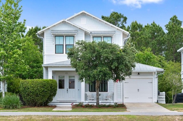 view of front of property featuring a standing seam roof, metal roof, covered porch, driveway, and an attached garage