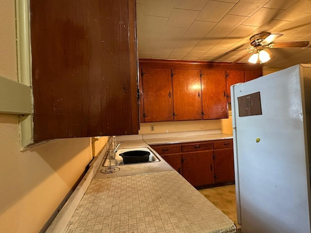 510 E Fisher St, Pensacola, FL 32503 - kitchen featuring a sink, ceiling fan, light countertops, freestanding refrigerator, and brown cabinetry