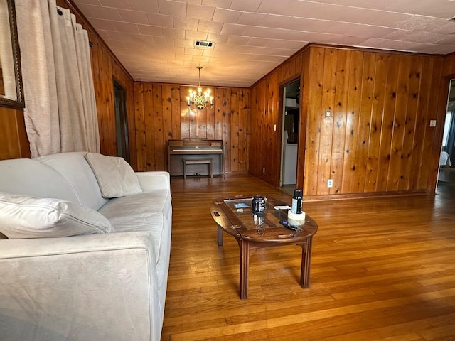 510 E Fisher St, Pensacola, FL 32503 - living room featuring visible vents, wood walls, an inviting chandelier, and wood-type flooring