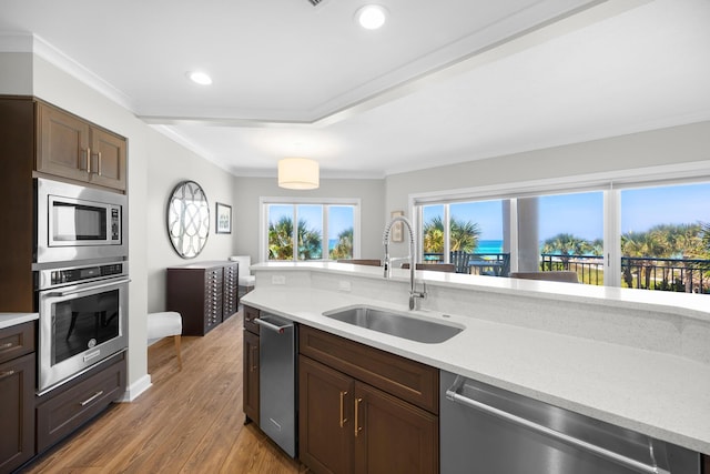kitchen with crown molding, appliances with stainless steel finishes, a sink, light countertops, and recessed lighting