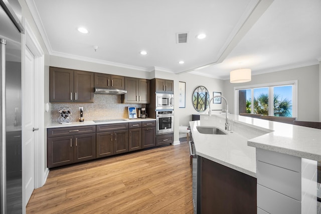 kitchen with dark brown cabinetry, a sink, light wood-style flooring, stainless steel appliances, and visible vents