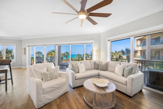 living area with baseboards, ornamental molding, a ceiling fan, and wood finished floors