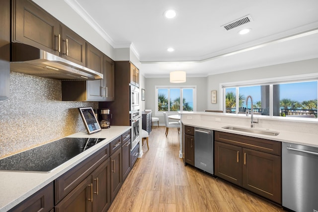 kitchen featuring dark brown cabinetry, a sink, stainless steel appliances, under cabinet range hood, and visible vents