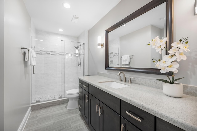 bathroom with vanity, toilet, recessed lighting, baseboards, and a stall shower
