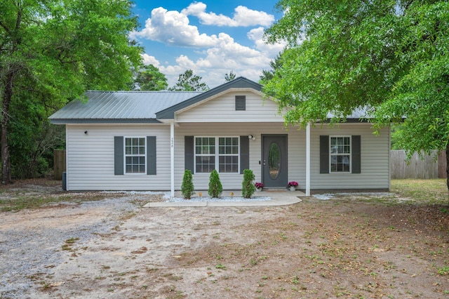 view of front of home featuring fence, covered porch, and metal roof