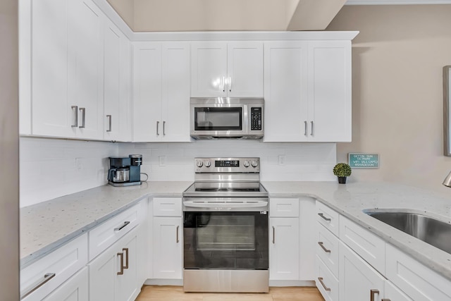 732 Scenic Gulf Dr Unit D103, Miramar Beach, FL 32550 - kitchen featuring a sink, tasteful backsplash, light stone counters, white cabinets, and appliances with stainless steel finishes