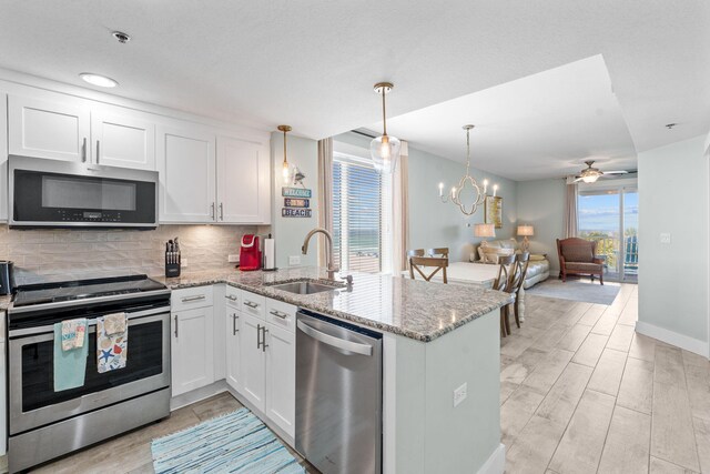 11807 Front Beach Rd # 1-309, Panama City Beach, FL 32407 - kitchen featuring decorative backsplash, a sink, appliances with stainless steel finishes, open floor plan, and a peninsula