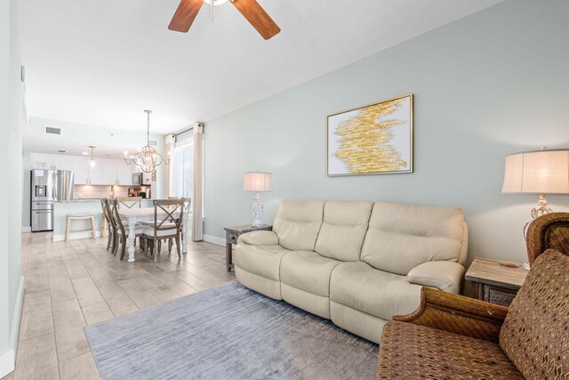 11807 Front Beach Rd # 1-309, Panama City Beach, FL 32407 - living area with visible vents, baseboards, light wood finished floors, and ceiling fan with notable chandelier