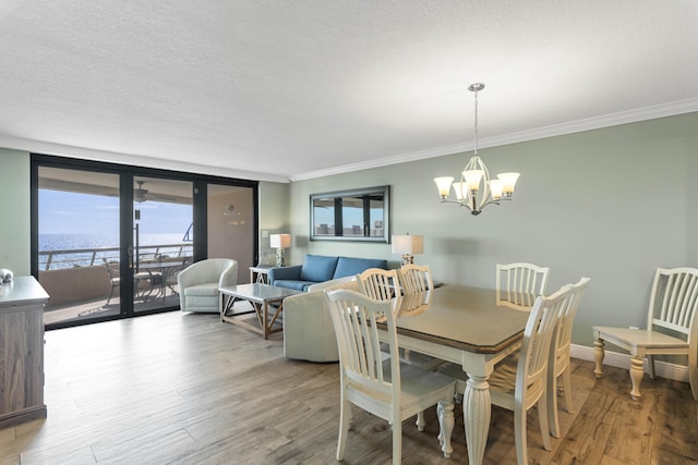 291 Scenic Gulf Dr Unit 900, Miramar Beach, FL 32550 - dining area featuring a chandelier, ornamental molding, wood finished floors, and a textured ceiling