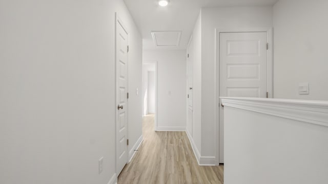 hallway featuring light wood finished floors, attic access, and baseboards