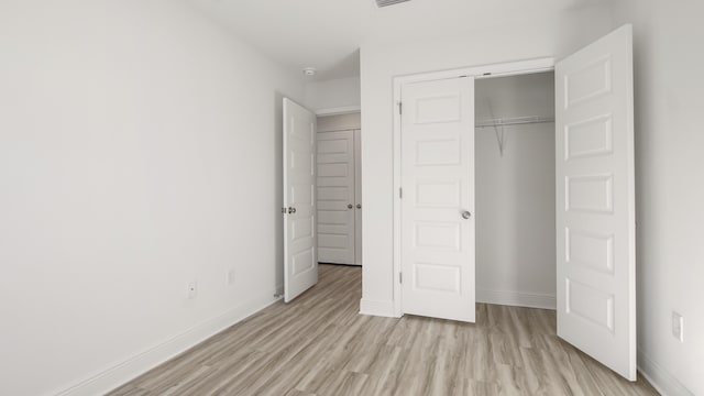 unfurnished bedroom with light wood-style flooring, baseboards, and a closet