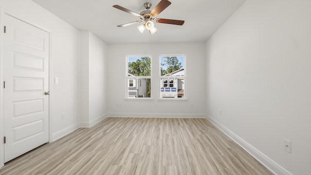 empty room featuring a ceiling fan, baseboards, and light wood-style floors
